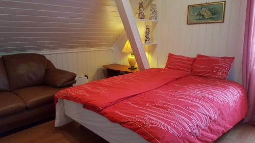 a bedroom with a red bed and a couch at Egil's Vacation House in Lillehammer