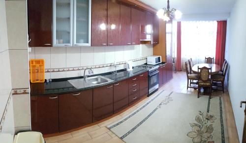 a kitchen with wooden cabinets and a table in it at Cima Apartment in Pristina