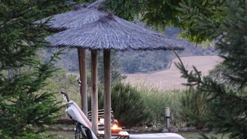 a straw umbrella and a chair under a table at Hotel Cardamomo Sigüenza in Carabias