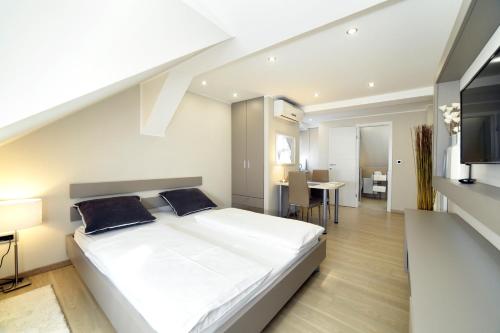 a bedroom with a large white bed and a dining room at D&G Apartments Zagreb in Zagreb