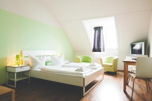 a bedroom with a bed and two chairs and a television at StayInn Hostel und Gästehaus in Freiburg im Breisgau