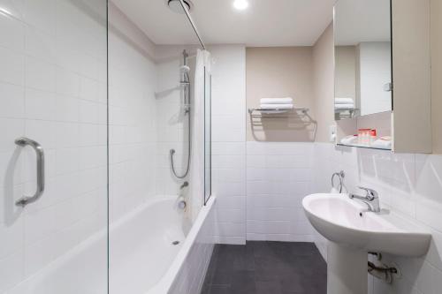 a white bathroom with a sink and a shower at The Chancellor on Hobson in Auckland