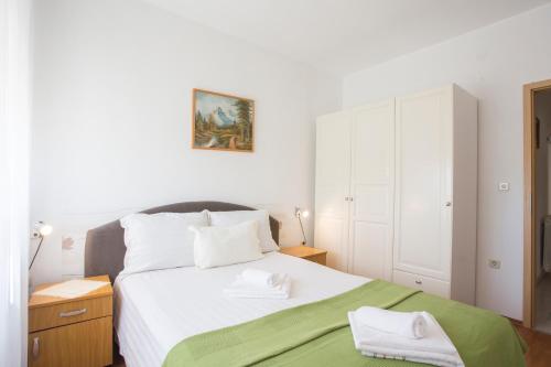 a bedroom with a large white bed with a green blanket at Guest House Croatia in Fažana