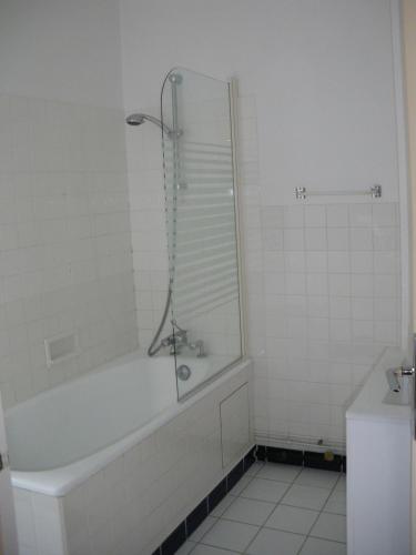a white bathroom with a tub and a sink at Hôtel Continental in Vierzon