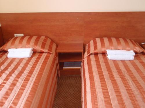 two beds in a hotel room with white towels at Hotel-Restaurant Smilga in Kėdainiai