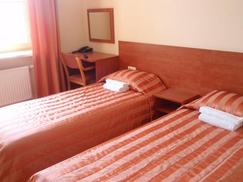 a hotel room with two beds and a desk at Hotel-Restaurant Smilga in Kėdainiai