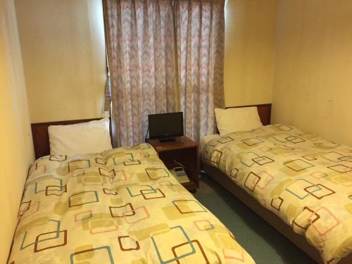 two beds in a room with a laptop on a table at Pension Moomin Papa in Myoko