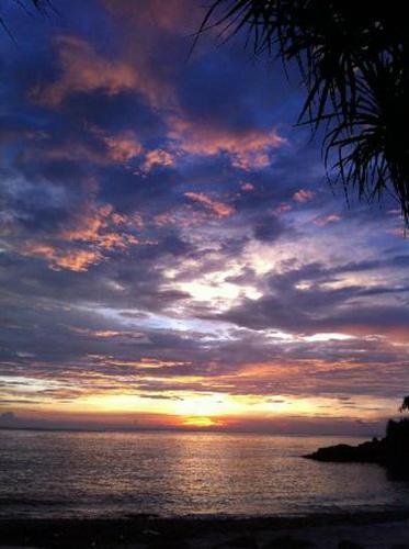 a sunset over the ocean with a cloudy sky at Lembongan Hostel in Nusa Lembongan
