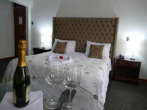 1 dormitorio con 1 cama y 2 copas de vino en Blub Hotel Spa, en Huancayo