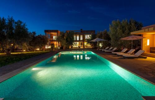 a swimming pool at night with chairs and umbrellas at Villa Kristy in Marrakech