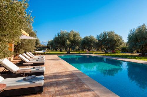 a swimming pool with chaise lounge chairs and trees at Villa Kristy in Marrakech