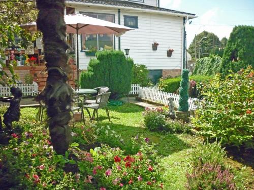 a garden with a table and chairs and flowers at Hostal y Cabañas Villa Germana in Puerto Varas