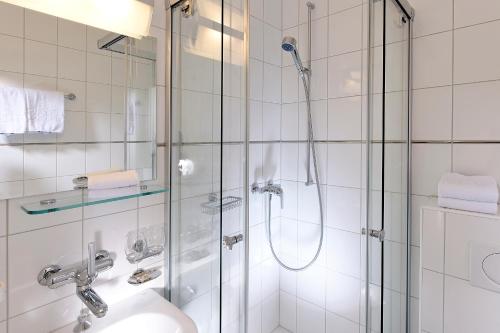 a white bathroom with a shower and a sink at Hotel Beausite Budget in Interlaken