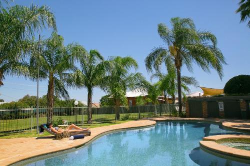 a man and a woman laying on a towel next to a swimming pool at Best Western Sanctuary Inn in Tamworth