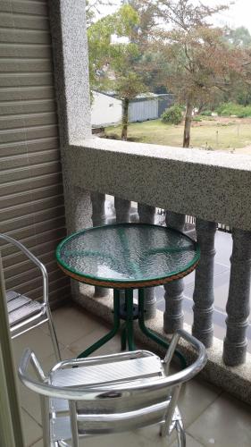 een glazen tafel en 2 stoelen op een balkon bij Loveplayer in Jinning