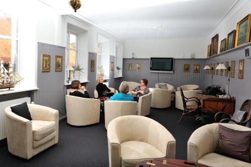 a living room filled with people sitting on couches at Hotel Gudhjem in Gudhjem