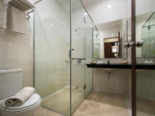 a bathroom with a shower and a toilet and a sink at The Victoria Hotel Yogyakarta in Yogyakarta