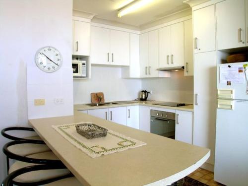 a kitchen with a table and a clock on the wall at Blue Waters Unit 8 59 Ronald Avenue in Shoal Bay