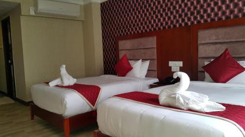 two swans sitting on two beds in a hotel room at Hyders Park The Business Hotel in Thanjāvūr