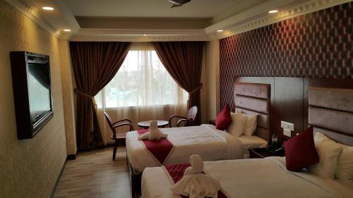 a hotel room with two beds and a television at Hyders Park The Business Hotel in Thanjāvūr