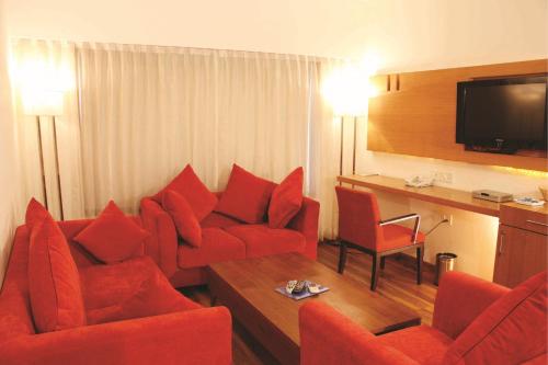 a living room with red chairs and a television at Gis Select Banjara Hill in Hyderabad