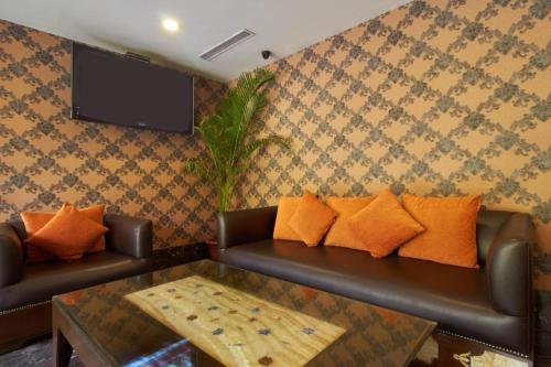 a living room with two leather couches and a tv at Gis Select Banjara Hill in Hyderabad