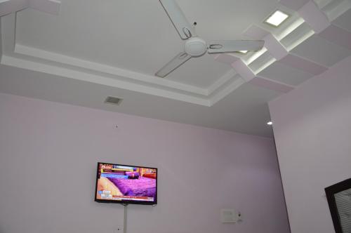 einen Deckenventilator und einen Flachbild-TV an einer weißen Wand in der Unterkunft Hotel Galaxy Inn in Jaipur