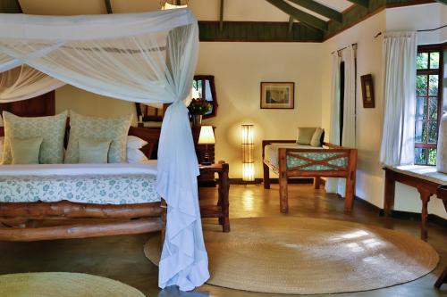 a bedroom with a bed with a canopy at Rivertrees Country Inn in Usa River