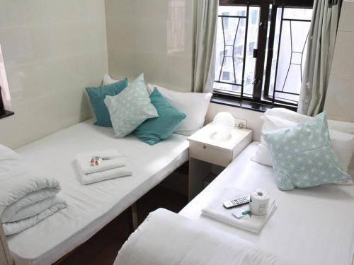 2 camas en una habitación con almohadas blancas y azules en New Yan Yan Guest House reception 9th floor Flat E4 E6, en Hong Kong