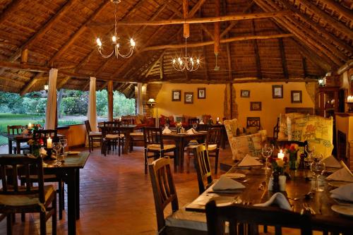 a restaurant with tables and chairs and chandeliers at Rivertrees Country Inn in Usa River