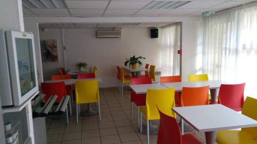 a dining room with tables and colorful chairs at Premiere Classe La Rochelle Sud - Angoulins in Angoulins