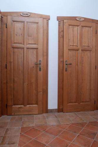 two wooden doors in a room with a tile floor at Pension Konírna in Huntířov