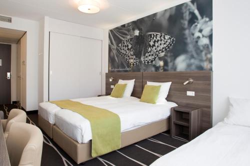 a hotel room with two beds and a chair at Hotel De Bonte Wever Assen in Assen
