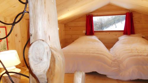 a bed in a log cabin with a window at La roulotte du bucheron in Lapoutroie