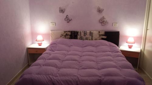 カステルサルドにあるVeryhouseの壁に2つの照明が付いたベッドルームの紫色のベッド1台