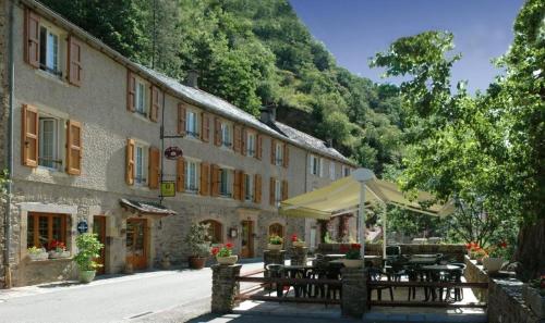 a group of tables and an umbrella in front of a building at Hôtel Restaurant Le Relays du Chasteau - Logis Hôtel in Brousse-le-Château