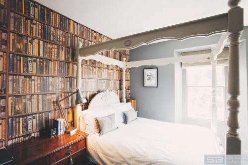 a bedroom with a bed and a wall of books at Rum Doodle, Windermere B&B in Windermere