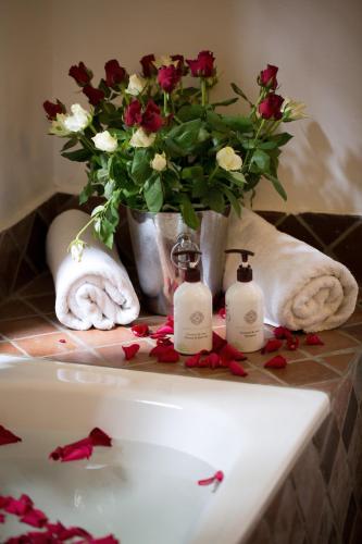a bathroom sink with a vase of flowers and towels at Rivertrees Country Inn in Usa River