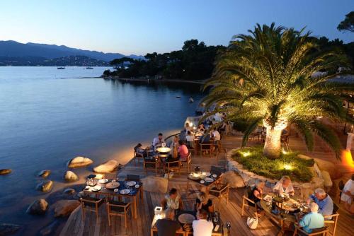 a group of people sitting at tables by the water at Hôtel Le Belvédère in Porto-Vecchio
