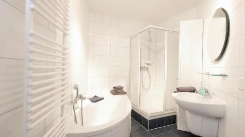 La salle de bains blanche est pourvue d'un lavabo, d'une baignoire et de toilettes. dans l'établissement Villa Vineta Whg. 207, à Ahlbeck