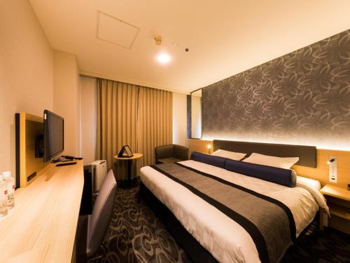 a hotel room with a bed and a flat screen tv at Shin Osaka Esaka Tokyu REI Hotel in Suita