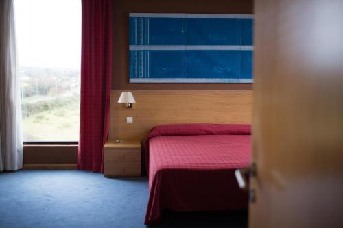 a bedroom with a bed with a red blanket and a window at Puerta de Santillana in Reocín