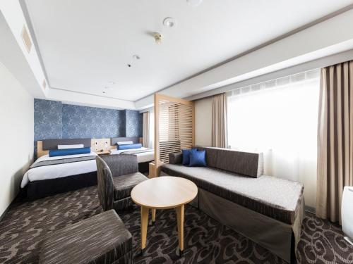 a hotel room with a bed and a couch at Shin Osaka Esaka Tokyu REI Hotel in Suita