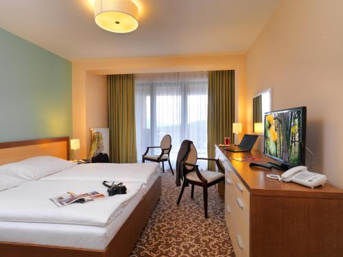 a hotel room with a bed and a desk with a computer at Hotel Green in Dolný Kubín