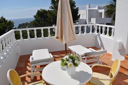 a patio with a table and an umbrella and chairs at Hotel Village in Cala Vadella