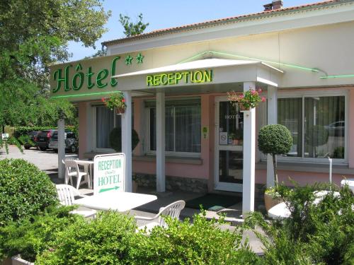 a hotel with chairs and a sign in front of it at Hotel Les Chênes in Sisteron