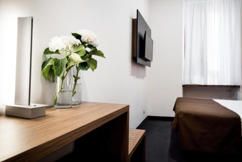 eine Vase mit weißen Blumen auf einem Holztisch in der Unterkunft Hotel Concordia in Rom