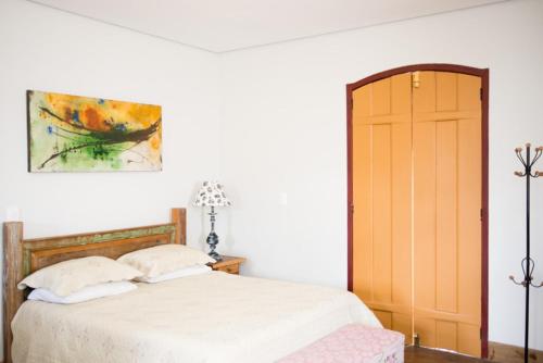 チラデンテスにあるLofts do Largoのベッドルーム1室(ベッド1台付)が備わります。壁には絵画が飾られています。