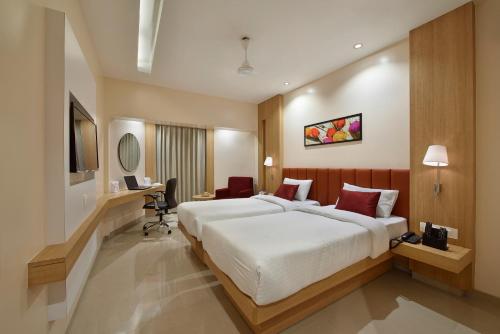 a hotel room with a large bed and a desk at The Eastern Hotel in Ankleshwar