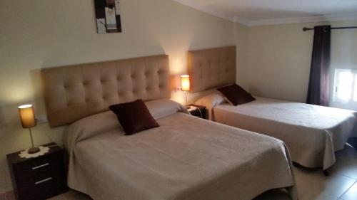 a hotel room with two beds and two lamps at Hostal Málaga in Arcos de la Frontera
